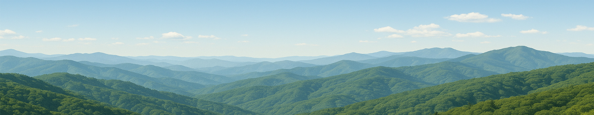 緑の稜線が幾重にも連なる初夏の低山パノラマ。青空に白い雲が浮かび、奥へ続く柔らかな山並みが広がっている。